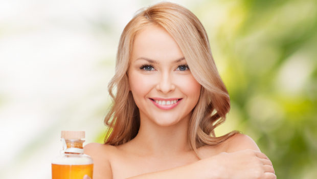 health-and-beauty-concept-happy-woman-with-oil-bottle-183525752.jpg